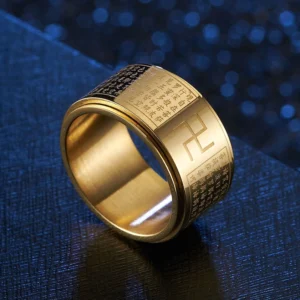 Gold Heart Sutra Swastika rotatable ring with engraved Buddhist mantra, shown from angled overhead view on dark textured backdrop