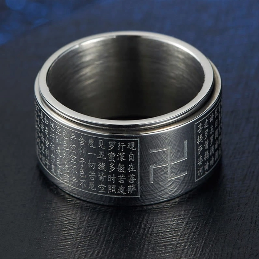 Silver Buddhist Heart Sutra Swastika rotatable ring from profile angle on neutral background