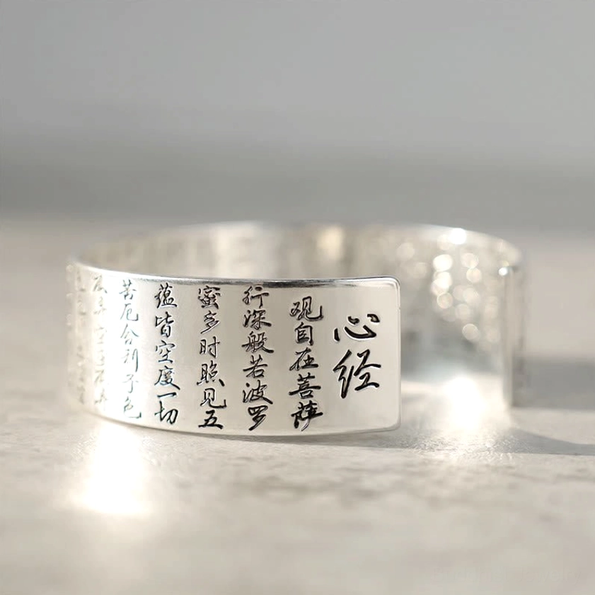 White copper Buddhist bracelet close-up showing Heart Sutra engravings on inner band with polished silver finish and protective spiritual design