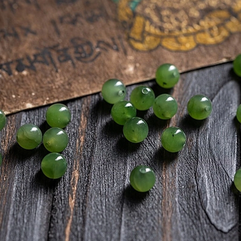 Loose cyan jade beads from Buddhist mala showing smooth round polish and natural color variation