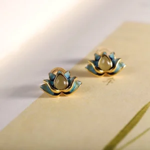Hetian cyan jade lotus stud earrings overhead flat lay with blue jade and gold trim on decorative background