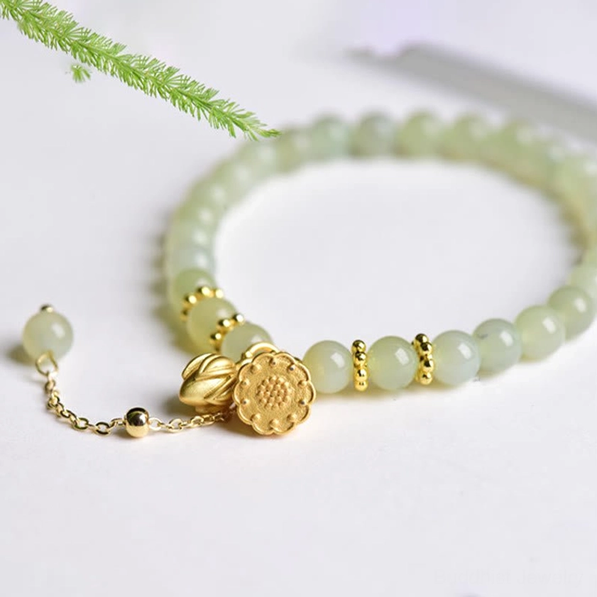 Close-up flat lay of light green jade beads with delicate gold lotus pod charms and adjustable chain