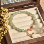 Hetian jade gourd lotus bracelet overhead flat lay with dried flowers on wooden jewelry tray