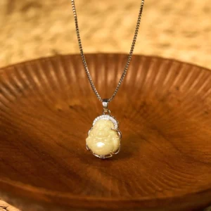 Natural pale yellow Hetian jade Laughing Buddha pendant necklace with silver frame and crystal accent stones, displayed on wooden background - authentic Buddhist prosperity pendant