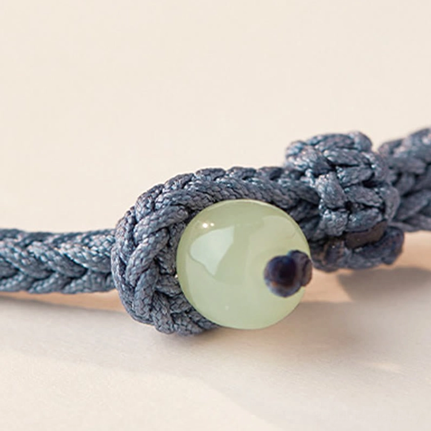 Complete view of Buddhist jade fortune bracelet with all decorative elements and braided cord