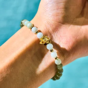 Hetian jade gradient lotus bracelet worn on wrist, showing seamless transition from green to white jade beads with gold lotus charm