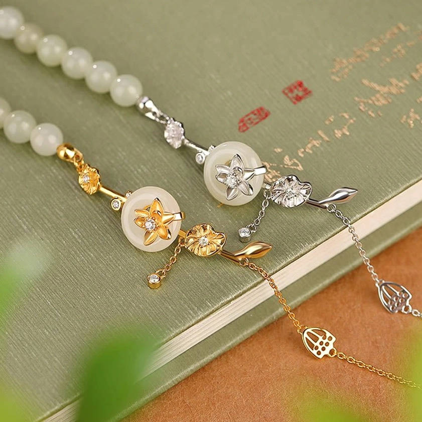 Dual-tone Hetian jade peace buckle bracelets in silver and gold finishes stacked on vintage books