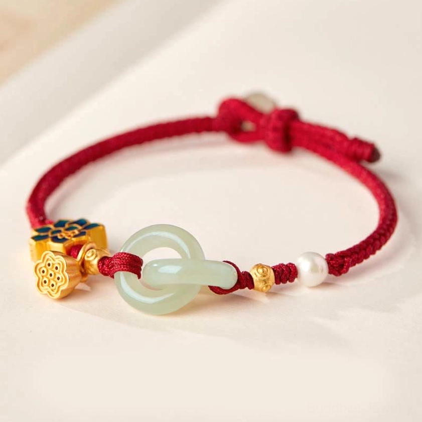 Hetian jade peace buckle lotus bracelet with red braided cord, enamel lotus charm, and pearl accent on neutral tabletop