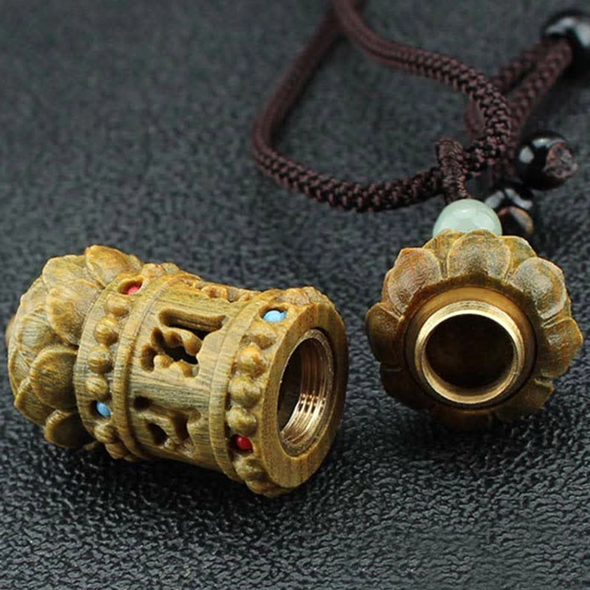 Hollow prayer wheel Buddhist pendant necklace with removable lotus cap and decorative colored stone inlays, top-down flat lay view