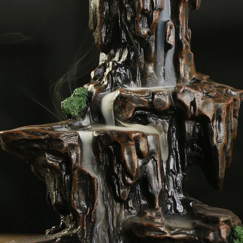 Close-up of Buddhist mountain incense burner showing rugged rock texture, detailed resin craftsmanship, moss decorations, and smoke flow
