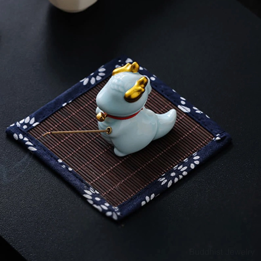 Dragon bell incense burner burning incense with aromatic smoke rising, top-down view on patterned tea mat