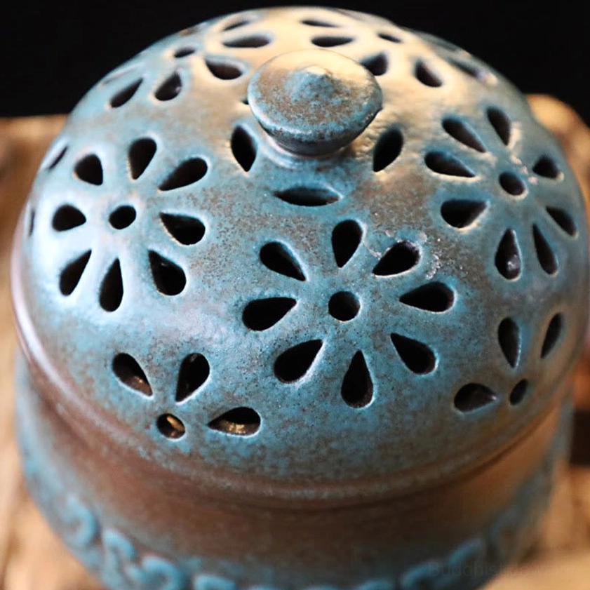 Extreme close-up of ceramic incense burner lid showing detailed floral hollow designs with matte two-tone ceramic texture and surface details