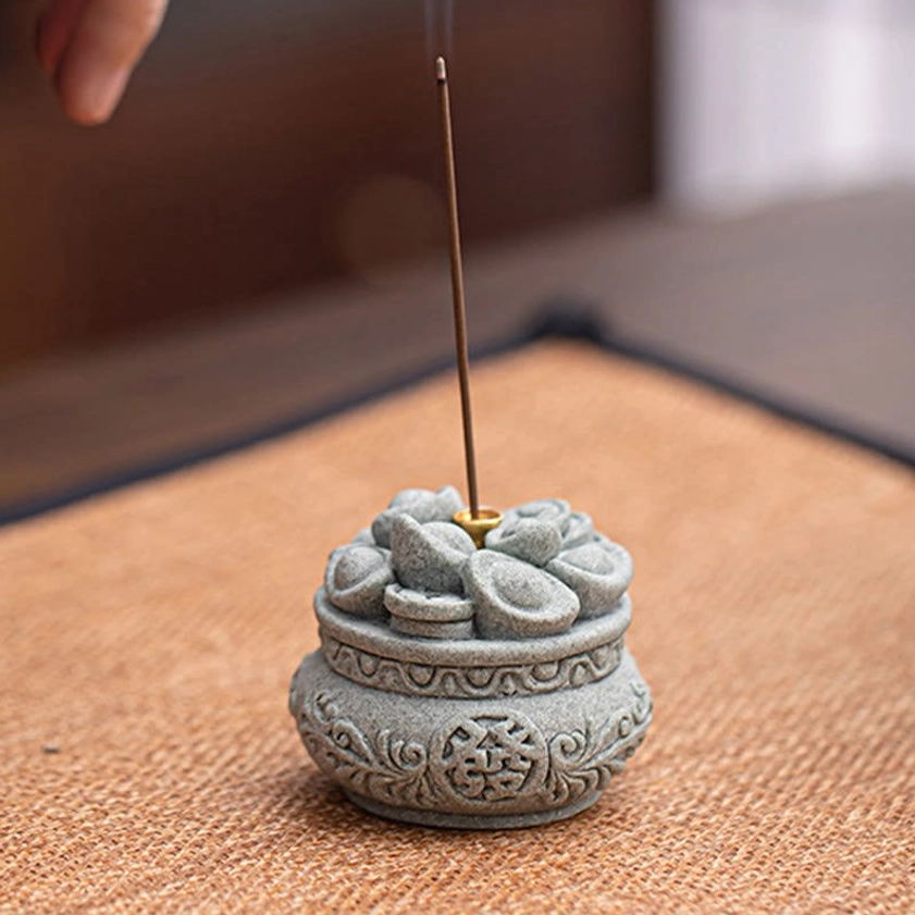 Natural sandstone incense holder with inserted incense stick and ingot top decoration on tea mat