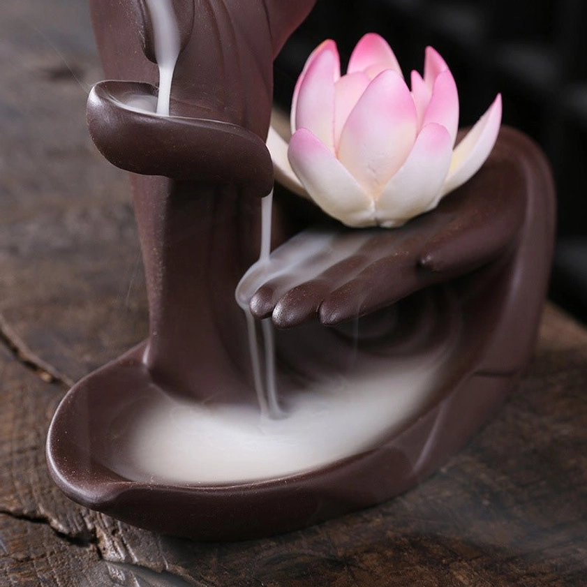 Close-up overhead view of ceramic incense burner showing flowing backflow smoke effect and pink lotus detail