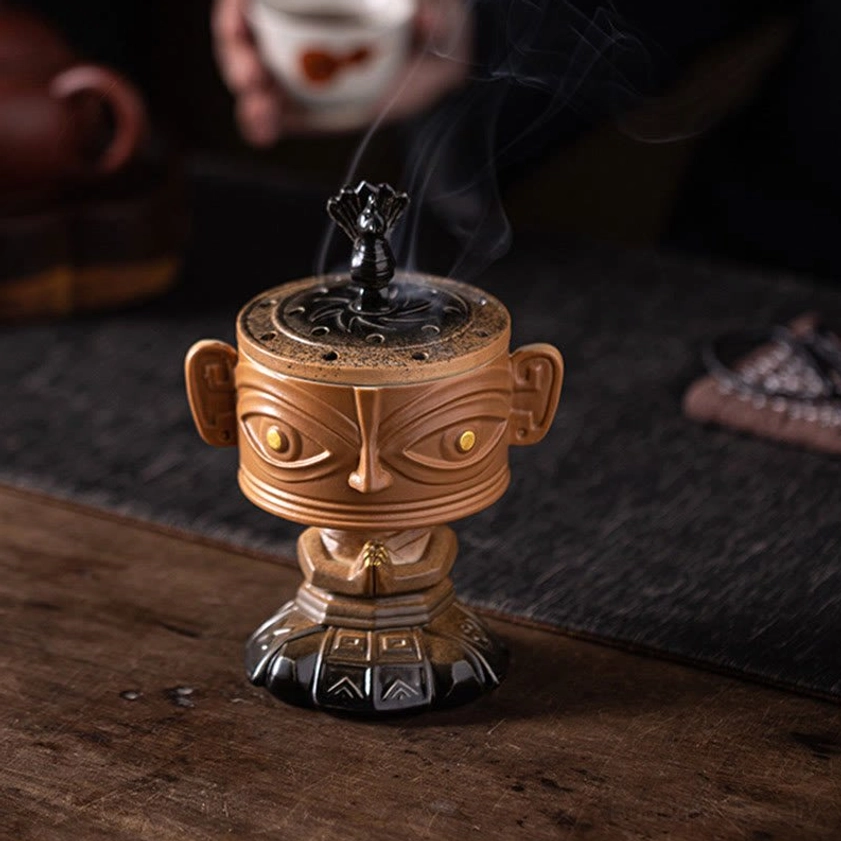 Smoking ceramic incense holder on dark meditation mat, traditional tea table setting with spiritual ambiance