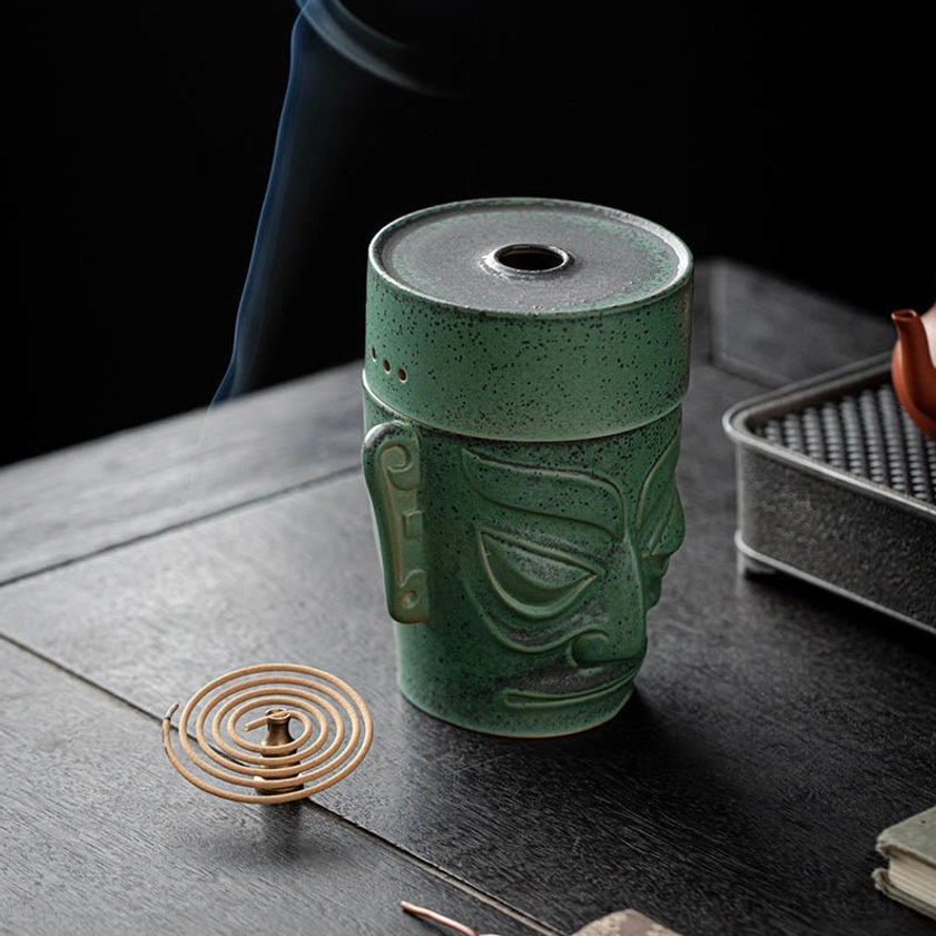 Right three-quarter view of ceramic incense burner with coil incense placed beside, smoke rising from the decorative piece