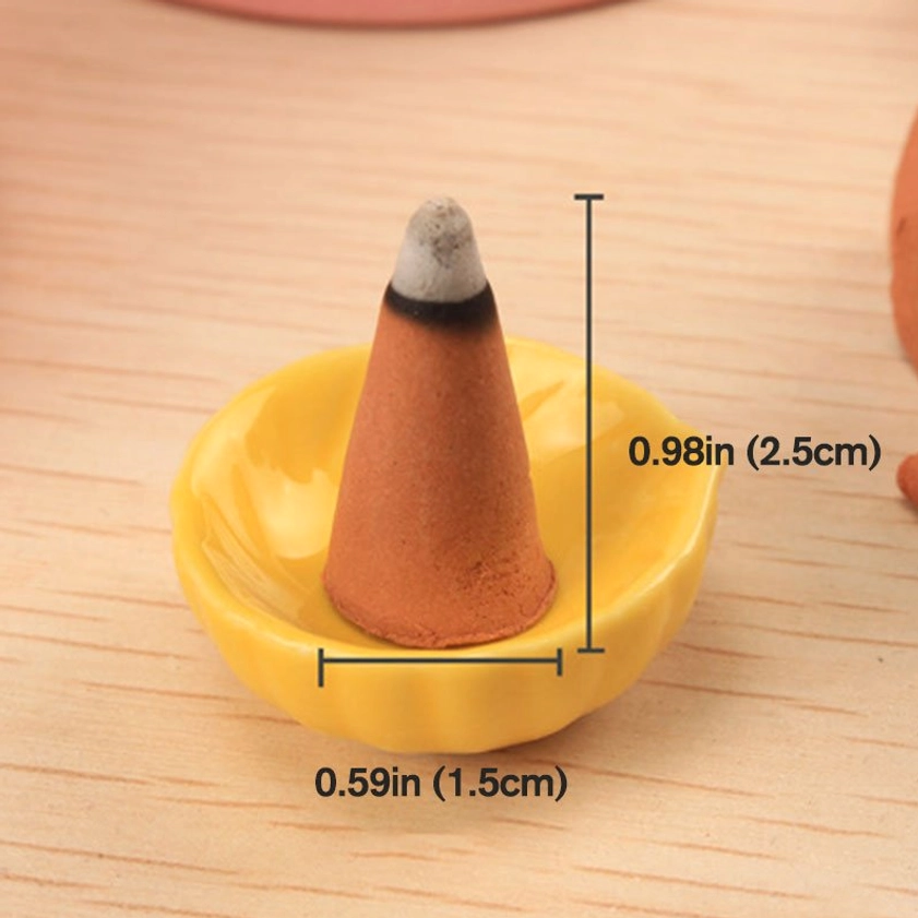 Burned incense cone on yellow holder showing size markings and ash, close-up demonstration