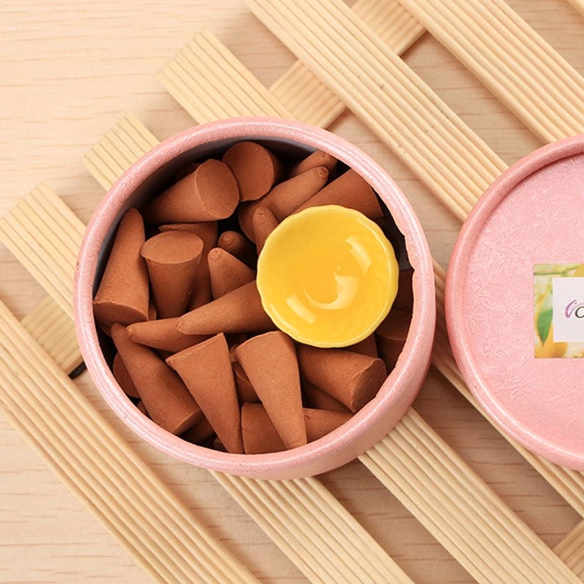 Open incense cone jar on wooden slatted mat displaying tapered brown cones with product label