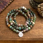 108 Indian agate mala beads bracelet with lotus pendant, flat lay view on wooden table with spiritual ornaments