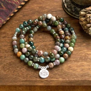 108 Indian agate mala beads bracelet with lotus pendant, flat lay view on wooden table with spiritual ornaments