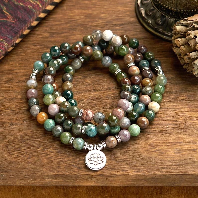 108 Indian agate mala beads bracelet with lotus pendant, flat lay view on wooden table with spiritual ornaments