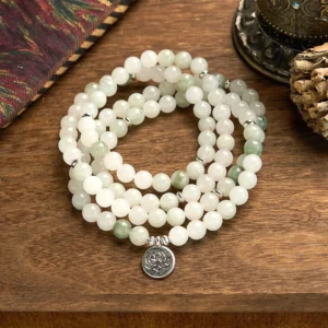 108 jade mala beads bracelet with silver lotus pendant on wooden surface, flat lay view showing white and green jade beads