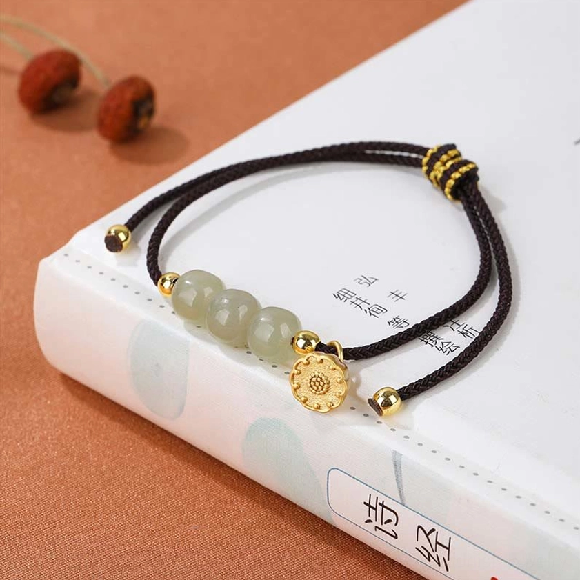 Black cord hetian jade beaded bracelet displayed on Chinese classic book with dried fruits, featuring gold decorative knot and lotus pod charm