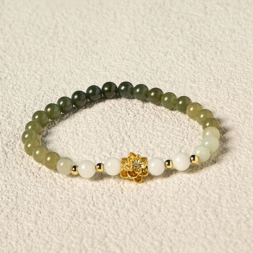 Hetian jade bracelet with white and green gradient beads, gold lotus charm with spacer details on light gray fabric
