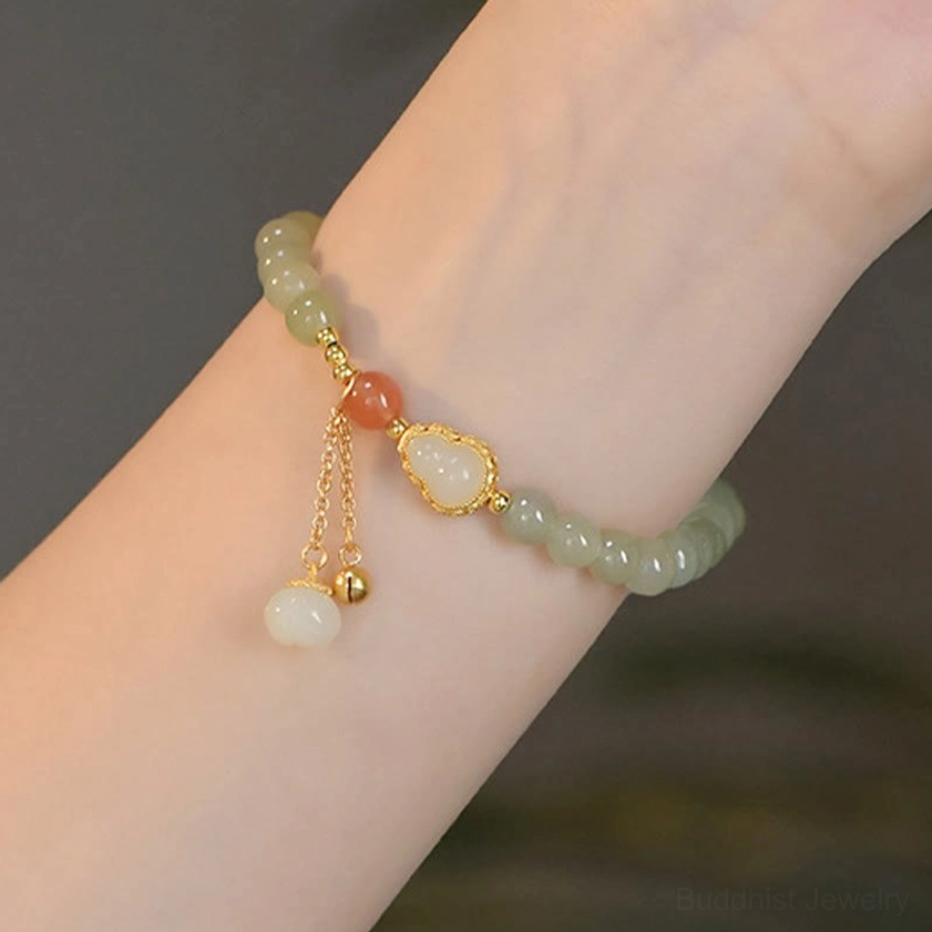 Jade beaded bracelet on arm featuring white jade pendant and gold gourd charm