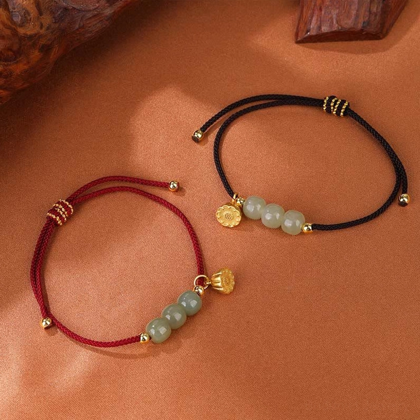 Dual-style comparison of jade bracelets showing red and black cord variants with jade beads and gold lotus charms arranged on warm brown fabric with wooden accents
