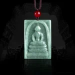 Jade Buddha square amulet pendant front overhead view, hand-carved formless Buddha design on natural bean-green jade with red bead cord