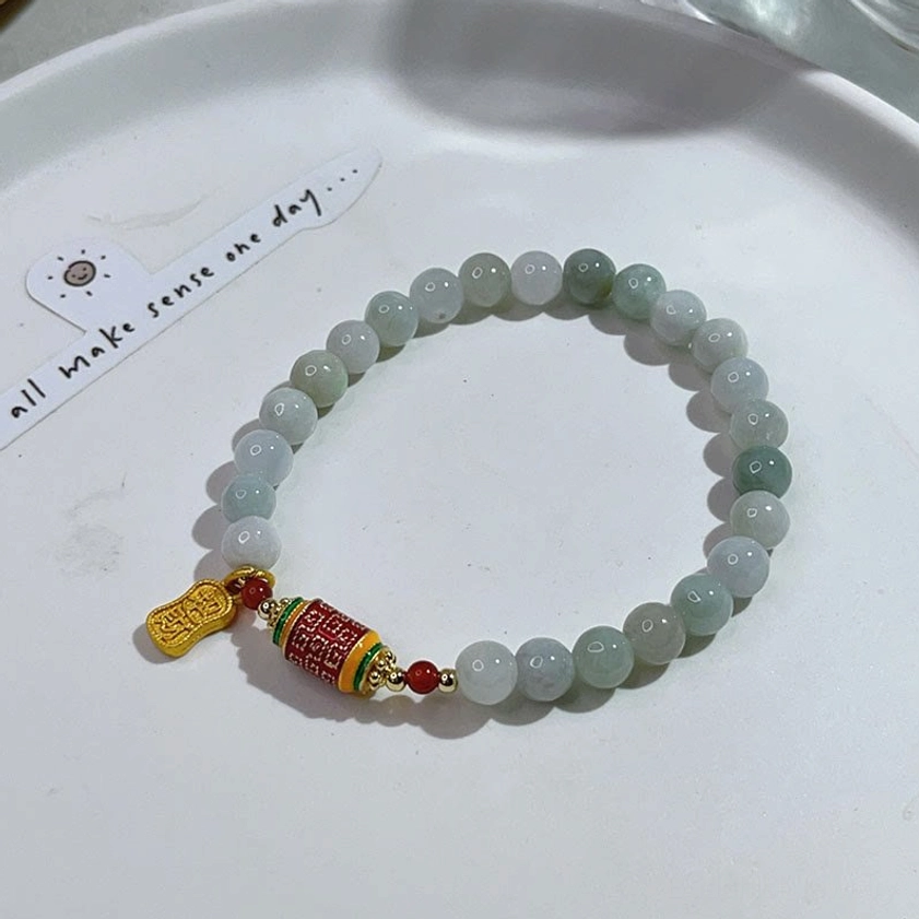 Ombre green jade beads with Buddhist prayer wheel and Fu pendant charm set on white ceramic plate