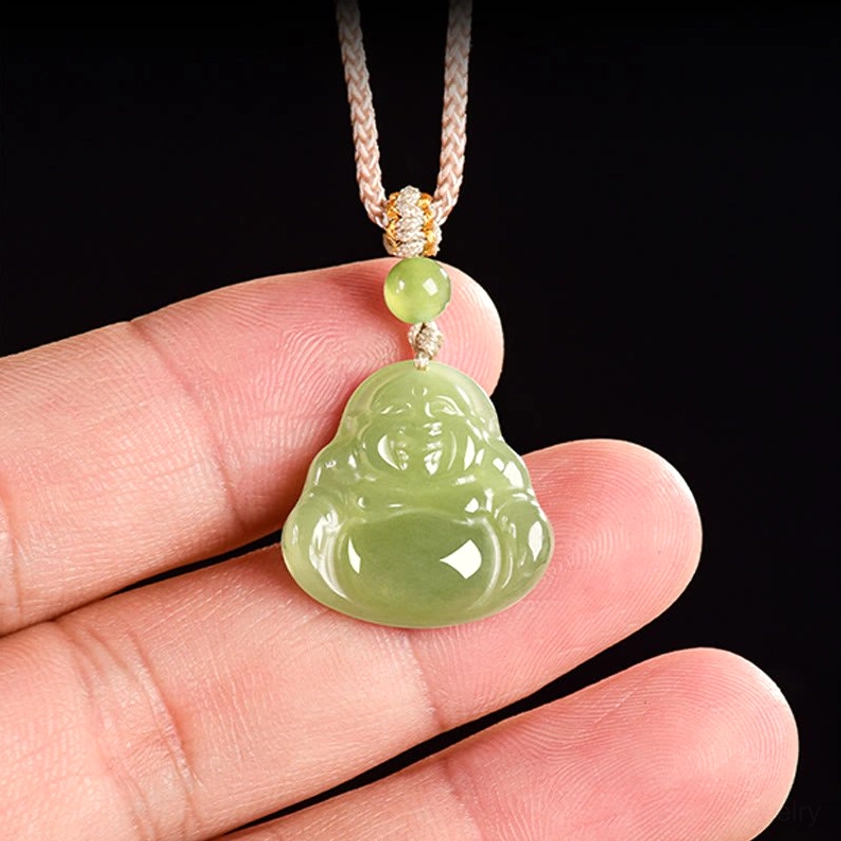 Close-up hand-held view of green jade laughing Buddha necklace pendant between fingers, demonstrating true size and smooth polished jade texture