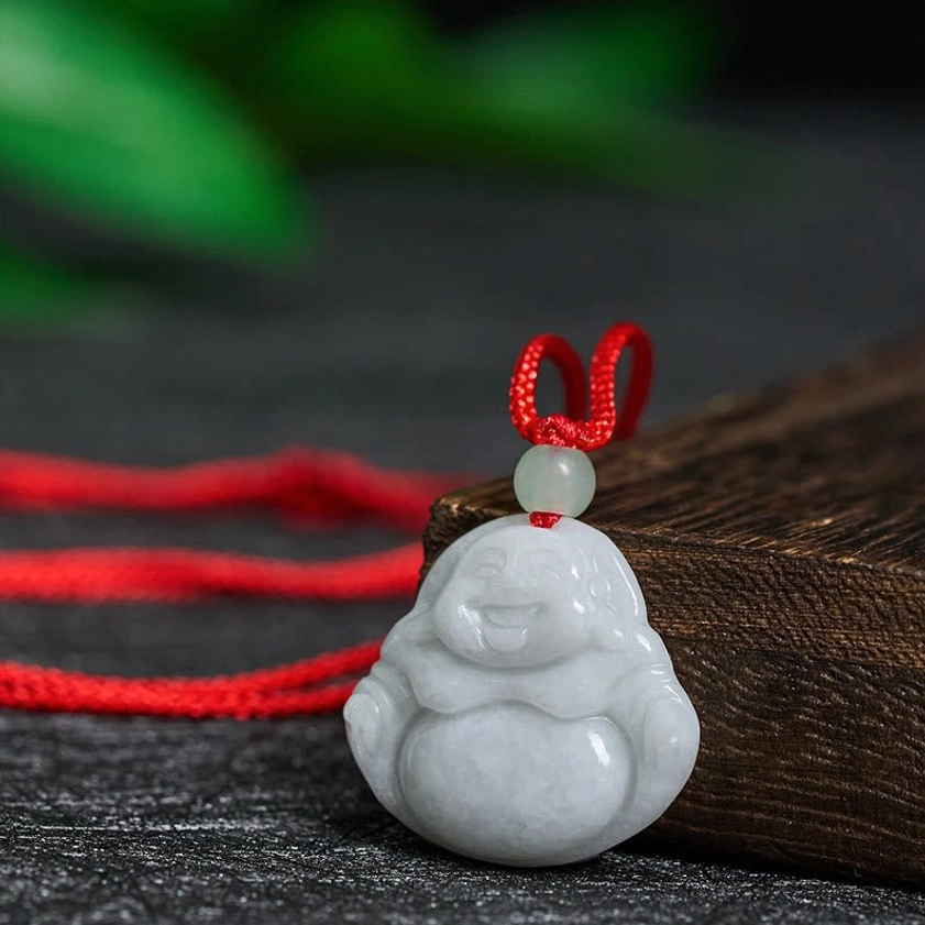 Three-quarter side view of carved jade Buddha pendant displaying smooth stone texture and braided red necklace cord