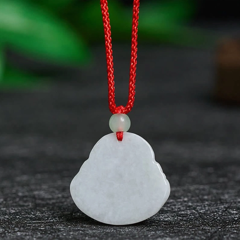 Back of jade Laughing Buddha pendant showing smooth uncarved flat surface and red cord attachment