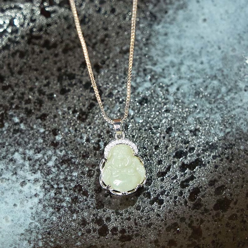 Natural light green Hetian jade Buddha pendant with box chain and silver crystal halo, frontal overhead view on textured grey ceramic - handcrafted Buddhist necklace for prosperity