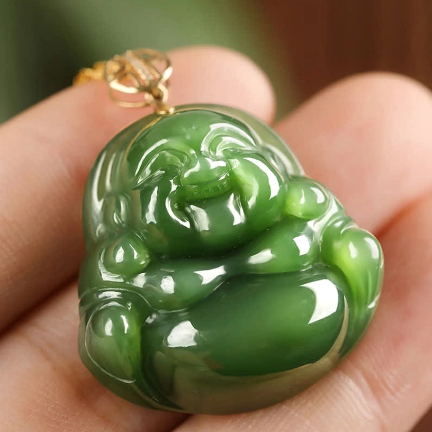 Close-up of Hetian jade Buddha pendant held on fingertips showing glossy polish and deep green color