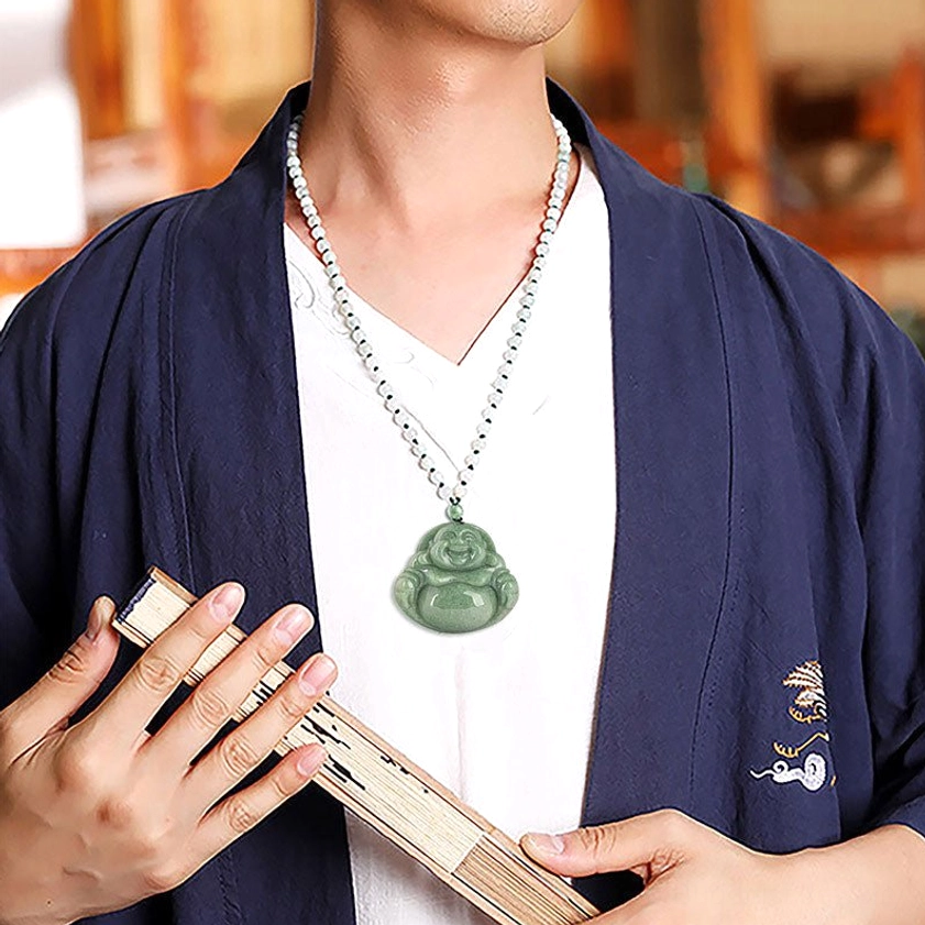 Elevated frontal view of cyan jade Buddhist pendant with white beaded cord on dark stone background