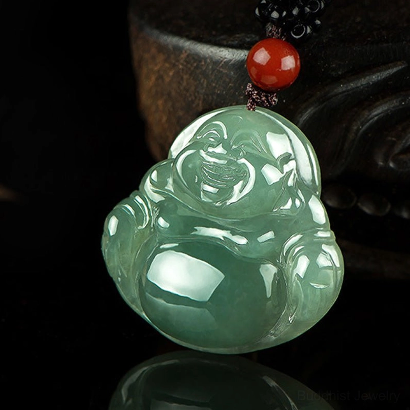 Light green jade Buddha pendant three-quarter front angle view showing carved facial features and decorative red black accessories clearly