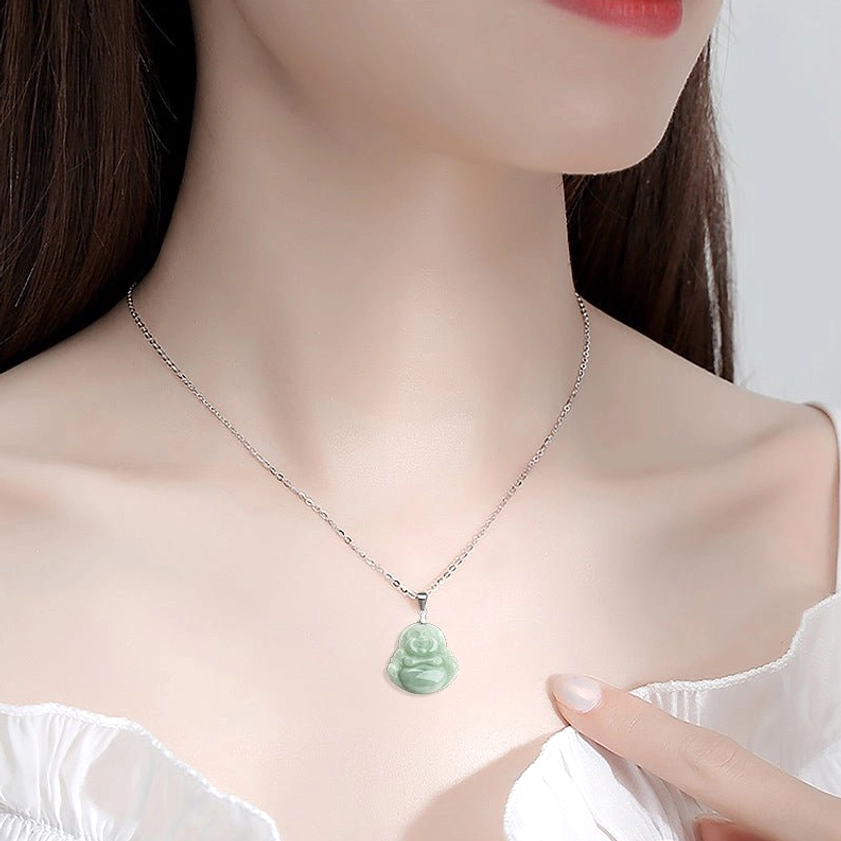 Woman wearing jade Laughing Buddha necklace close-up on neck with thin silver chain light green pendant and white clothing