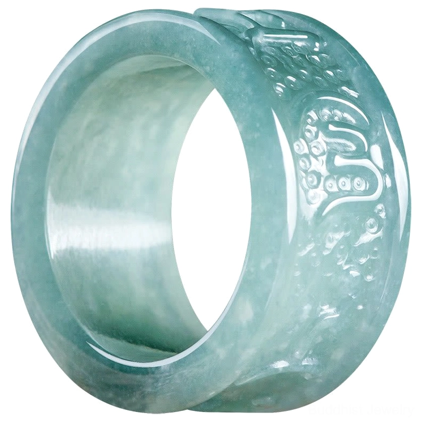 Extreme close-up of carved jade Buddhist ring showing detailed natural jade grain texture, fine hand-engraved Om Mani Padme Hum mantra patterns and polished surface