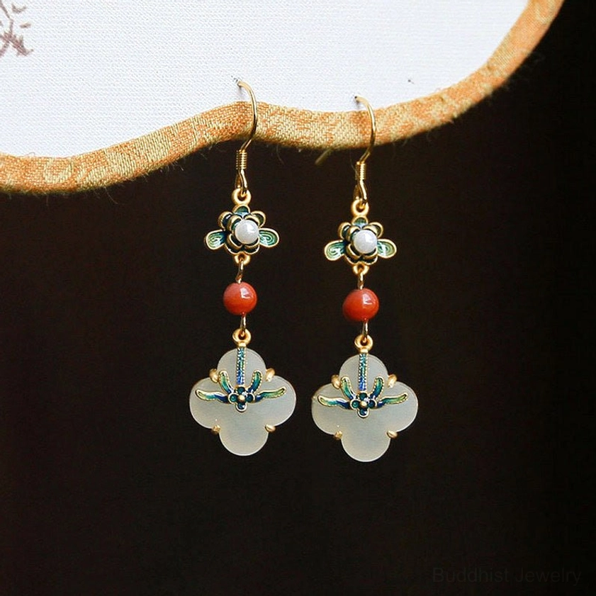 Jade four-leaf clover drop earrings displayed on Chinese-style frame background, showing pearl-inlaid enamel details