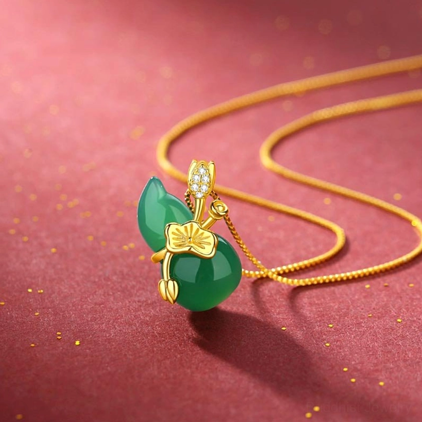 Cyan jade Buddhist gourd necklace with lotus decor side angle, gold chain with diamond accents on red glittery background