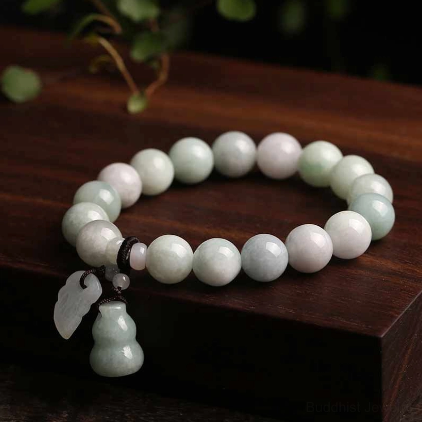Artisan jade gourd bracelet with off-white and light green natural jade beads and single gourd pendant on dark wooden display