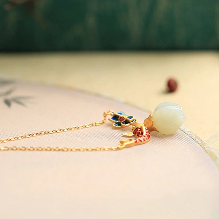 White jade koi fish lotus Buddhist necklace complete pendant and chain displayed flat on Chinese ink painting style tabletop