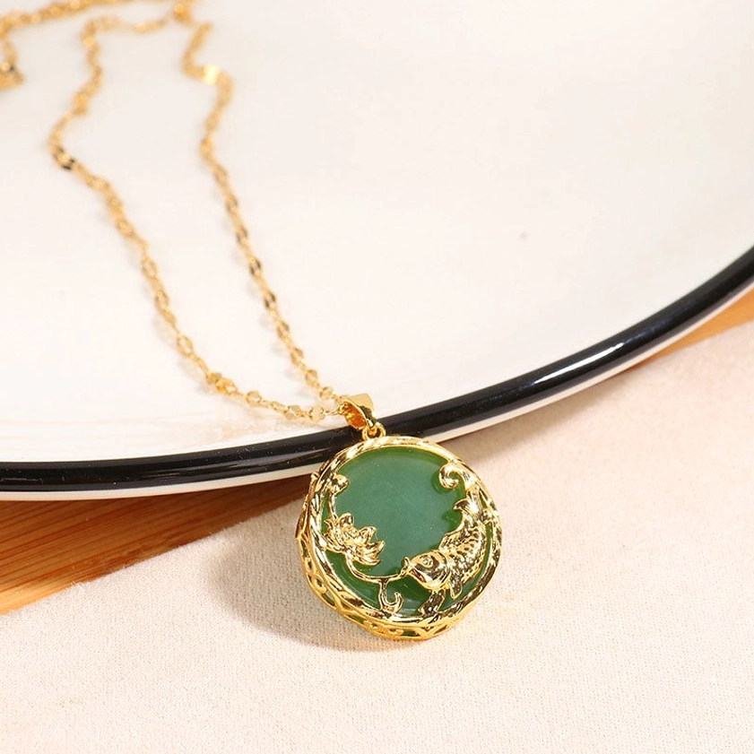 Natural jade koi necklace with twisted gold chain and round pendant displayed on wooden surface