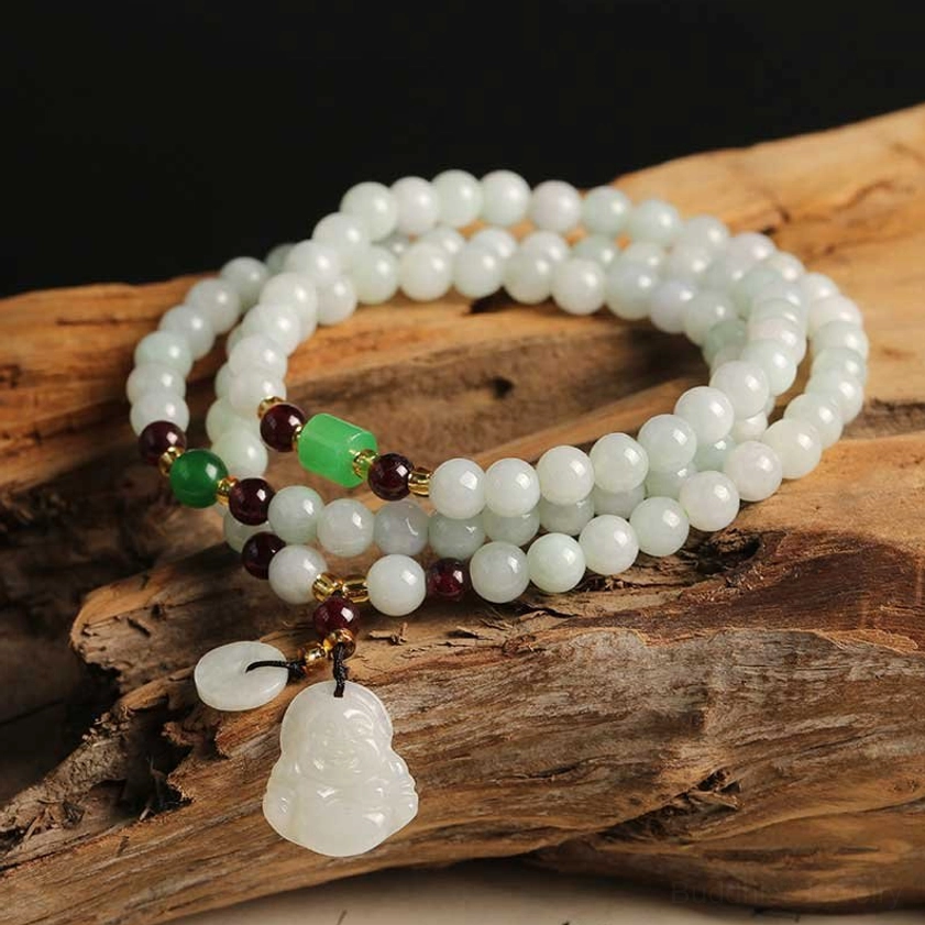 Laughing Buddha jade pendant bracelet resting on weathered wood slab, featuring light jade beads, metal-spaced red and green accents, and Buddha-shaped charm