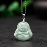 Natural jade Laughing Buddha pendant necklace front view flat lay with light green Maitreya carved jade and silver clasp on dark background