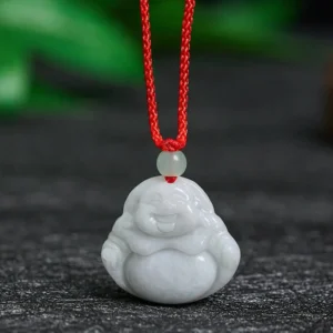 Jade Laughing Buddha pendant necklace with red silk cord on wooden table - front view showing intricate hand-carved details