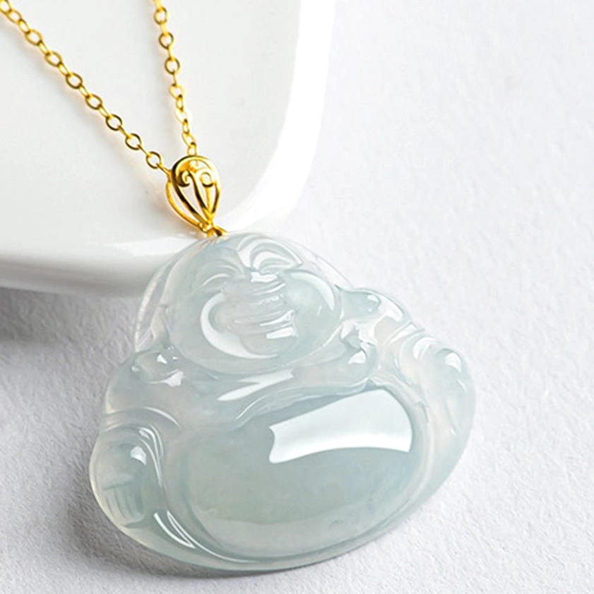 Front oblique view of light green jade Laughing Buddha pendant with ornate gold bail on white background, flat lay display